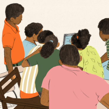 group of children around a laptop in a classroom