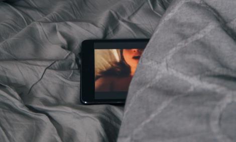 Image description: Tablet lying on bed, image of woman on the screen