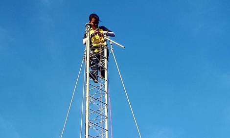 Image description: A person high up on a communications tower
