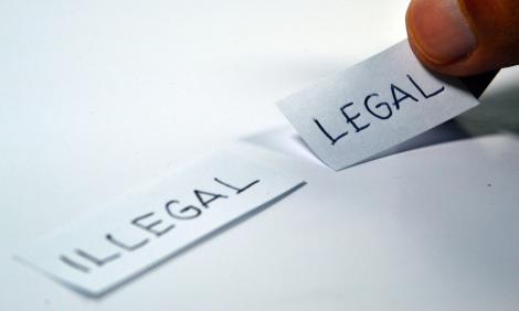 photo of a hand handling two labels saying "legal" and "illegal"