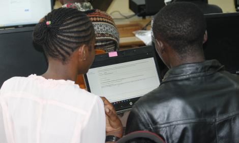 The backs of two people looking at a computer - a woman and a man