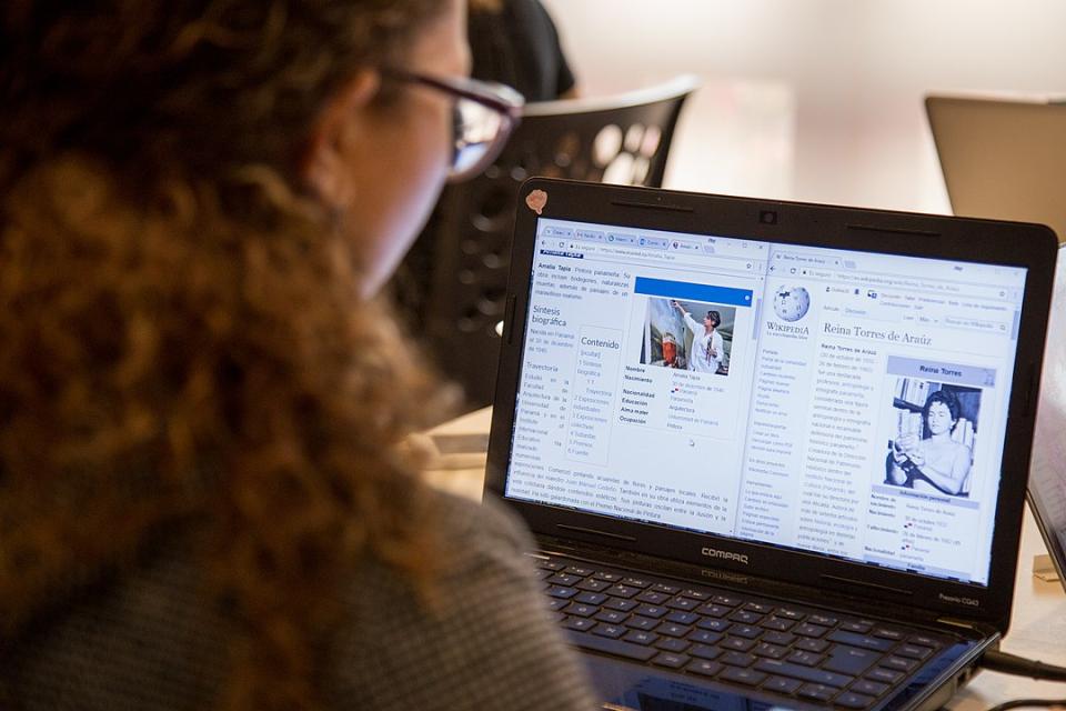 Mujer frente al monitor editando una entrada de Wikipedia