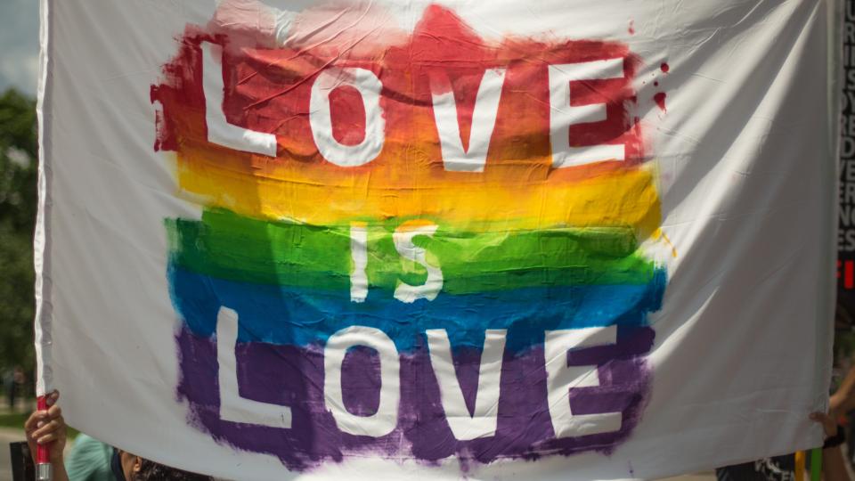 Banner saying Love is Love on rainbow background 
