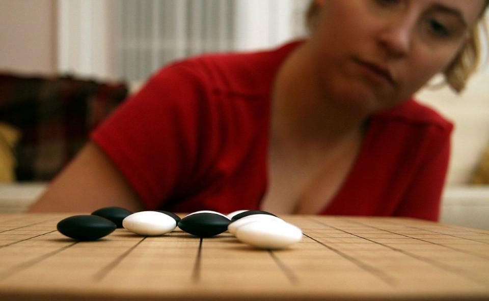Woman considers a play in a Go board