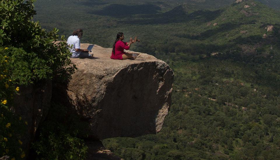 Image description: Two people check equipment on top of hill