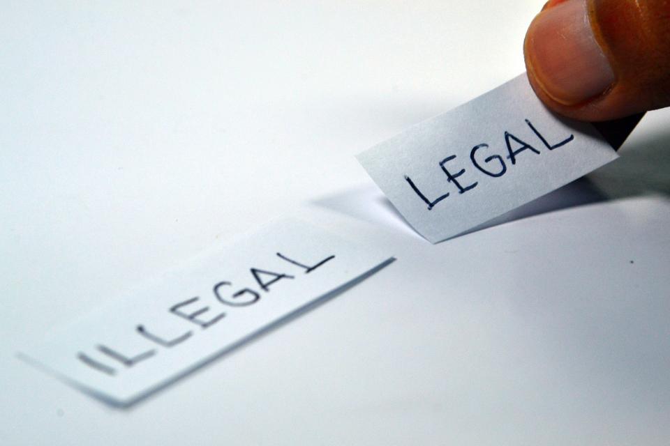 photo of a hand handling two labels saying "legal" and "illegal"