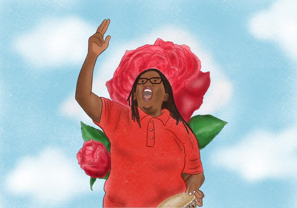 Stella Nyanzi rising her hand, with roses at her back.