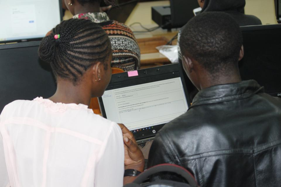 The backs of two people looking at a computer - a woman and a man
